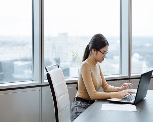 Person working on a laptop beside a bright window in Peru