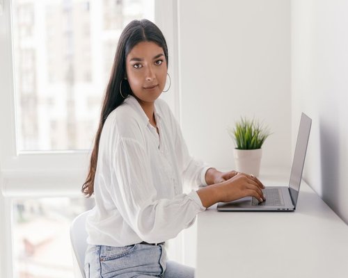 Person working on a laptop beside a bright window in Peru